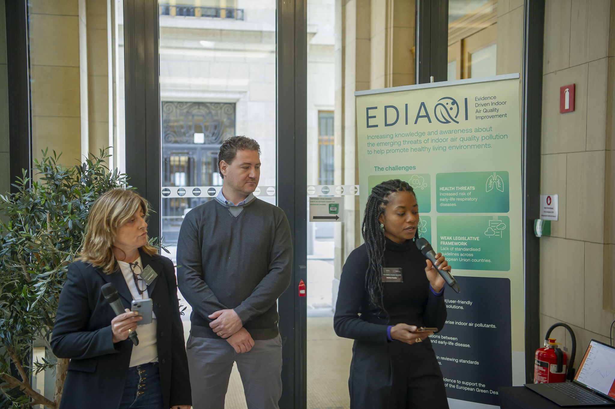 Andrea Cuesta presents the EDIAQI project during the IDEAL Cluster Marketplace at the IDEAL Cluster Summit – The Air We Share in Brussels. Standing beside the EDIAQI exhibition stand, she introduces the project's research, tools and key outcomes, inviting participants to explore how EDIAQI is contributing to healthier indoor environments through evidence, innovation and collaboration.