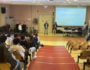 Image of the auditorium, the presenters, and students at 