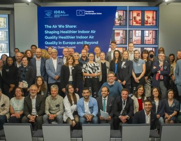 Participants gather for a group photograph at the IDEAL Cluster Summit – The Air We Share: Shaping Healthier Indoor Air Quality in Europe and Beyond in Brussels. Researchers, policymakers, industry representatives, public authorities and civil society organisations from across Europe stand together in front of the Summit stage, representing the seven Horizon Europe projects of the IDEAL Cluster and celebrating their shared commitment to advancing healthier indoor environments through research, innovation an