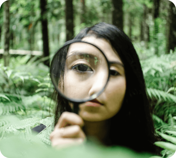 A woman using a magnifying glass in a forest